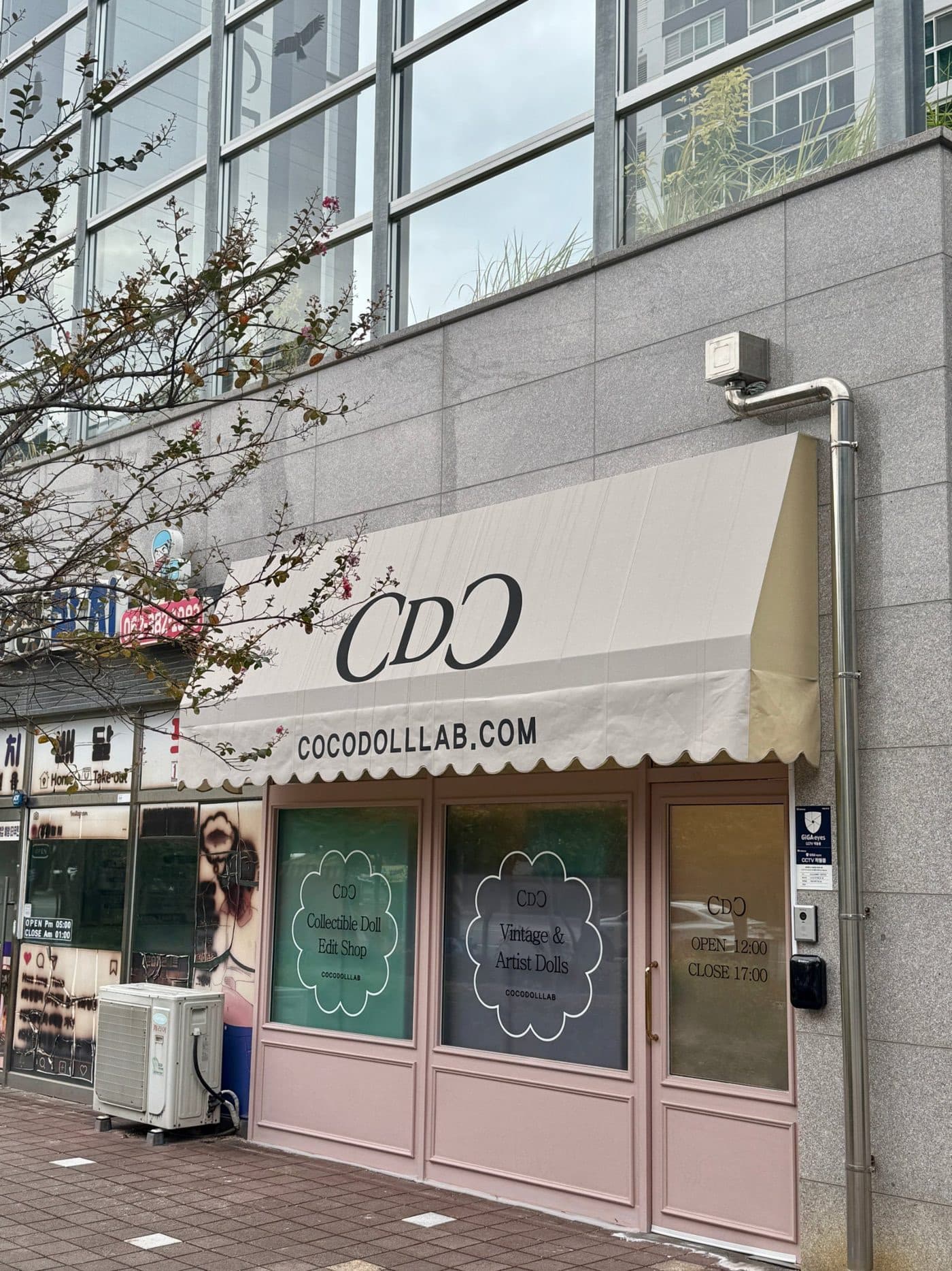 스캘럽 어닝과 분홍색 문이 있는 코코돌랩 매장 외관